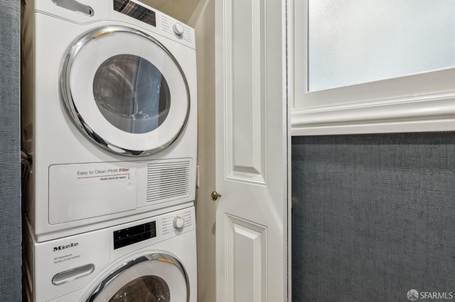 clothes washing area with stacked washer / dryer and laundry area