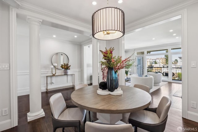 dining space featuring ornamental molding, wood finished floors, and decorative columns