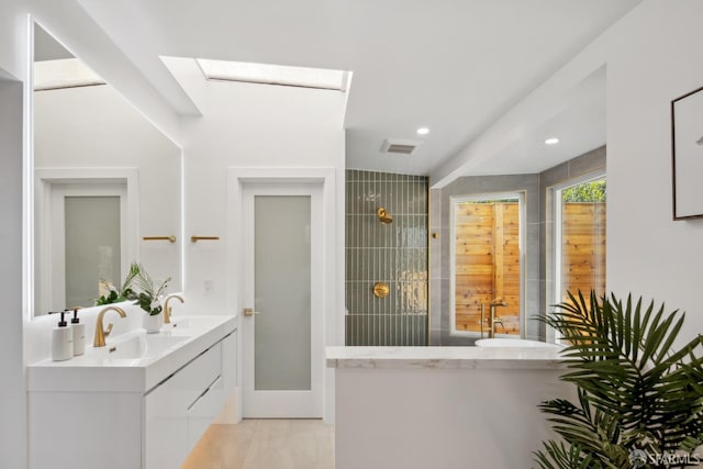 bathroom with vanity, a skylight, and a tile shower