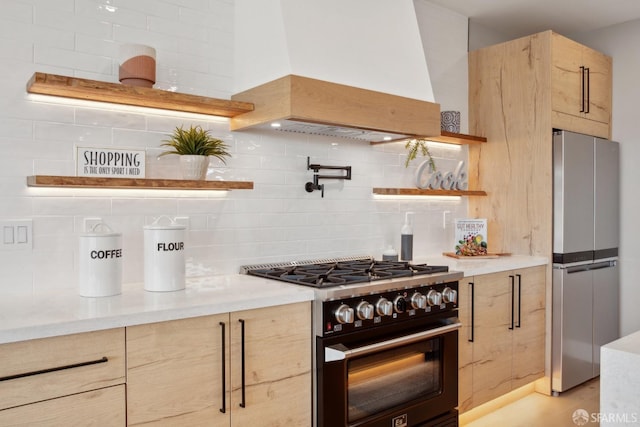 kitchen featuring stainless steel refrigerator, premium range hood, light brown cabinetry, and gas stove