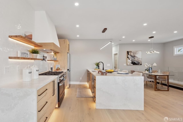 kitchen with sink, appliances with stainless steel finishes, tasteful backsplash, decorative light fixtures, and light wood-type flooring