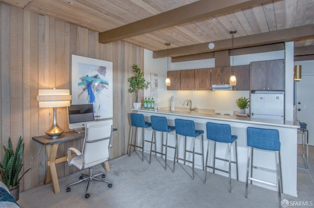 kitchen with pendant lighting, beamed ceiling, white fridge, kitchen peninsula, and a breakfast bar area