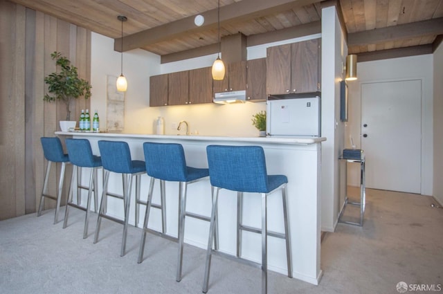 kitchen featuring light colored carpet, hanging light fixtures, kitchen peninsula, and beam ceiling