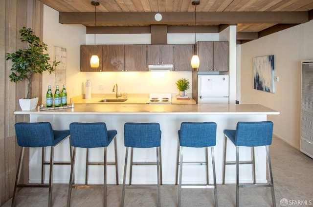 kitchen with kitchen peninsula, sink, beamed ceiling, hanging light fixtures, and white refrigerator