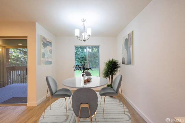 dining room with light wood-type flooring, plenty of natural light, a chandelier, and baseboards