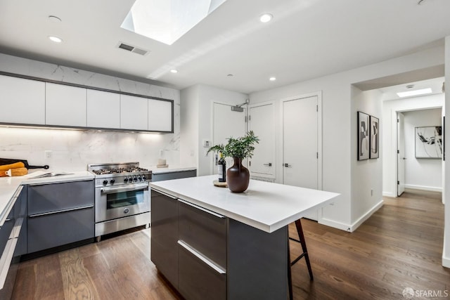 kitchen featuring high end range, visible vents, modern cabinets, and a breakfast bar area