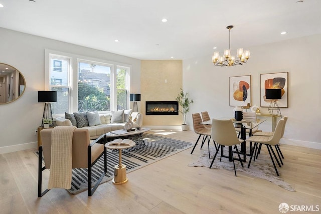 dining space featuring light hardwood / wood-style floors, an inviting chandelier, and a large fireplace