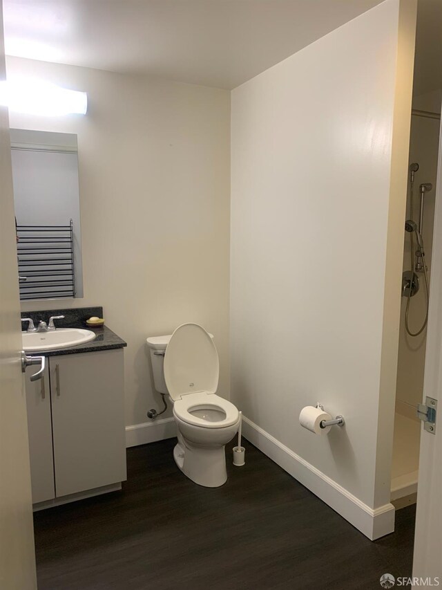 bathroom featuring walk in shower, vanity, toilet, and hardwood / wood-style flooring