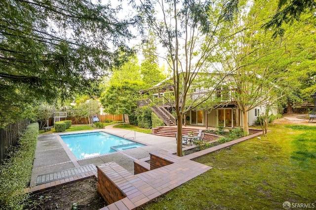 view of swimming pool with a lawn, a deck, a fenced backyard, stairs, and a pool with connected hot tub
