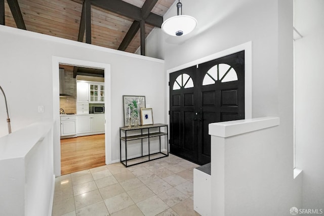 foyer entrance featuring beam ceiling, high vaulted ceiling, wood ceiling, and light tile patterned floors