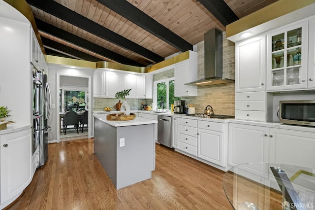 kitchen featuring wall chimney range hood, a kitchen island, wooden ceiling, and appliances with stainless steel finishes