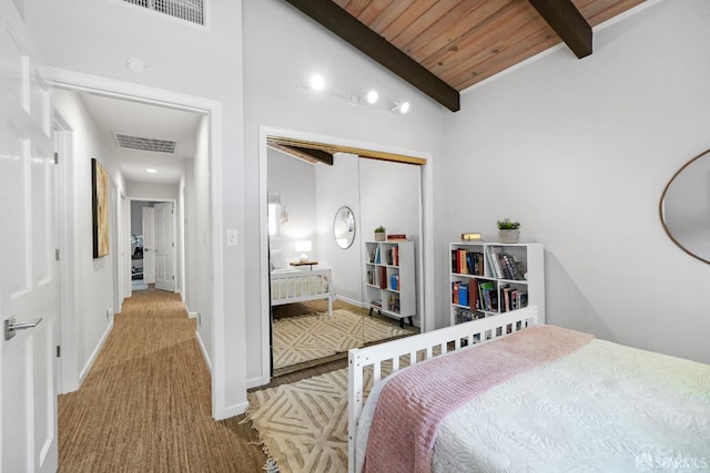bedroom featuring vaulted ceiling with beams, visible vents, carpet, a closet, and wood ceiling