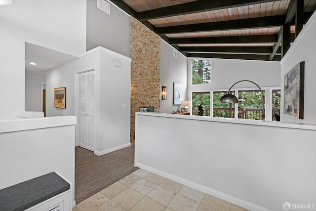interior space featuring beamed ceiling, baseboards, wooden ceiling, a high ceiling, and visible vents