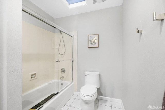 full bathroom featuring shower / bath combination with glass door, tile patterned floors, toilet, a skylight, and baseboards