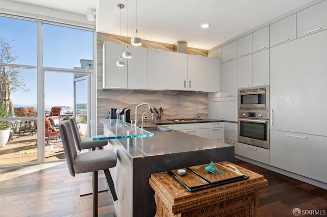 kitchen featuring hanging light fixtures, sink, white cabinets, and stainless steel appliances