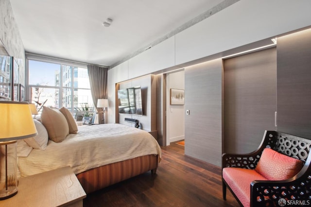 bedroom with dark hardwood / wood-style floors and expansive windows