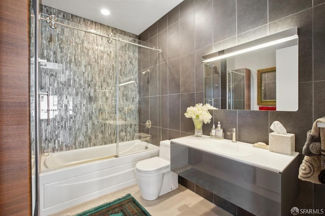 full bathroom featuring backsplash, vanity, shower / bath combination with glass door, tile walls, and toilet