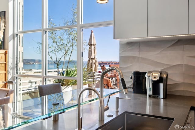 kitchen with expansive windows, plenty of natural light, a water view, and sink