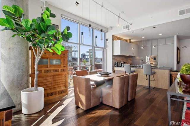 dining area with rail lighting and dark wood-type flooring