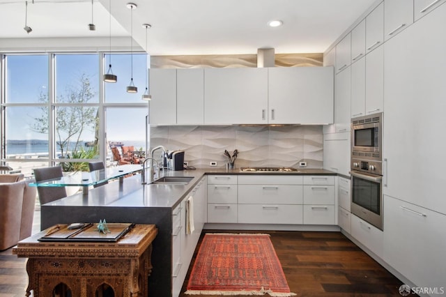 kitchen with pendant lighting, white cabinetry, sink, and stainless steel appliances