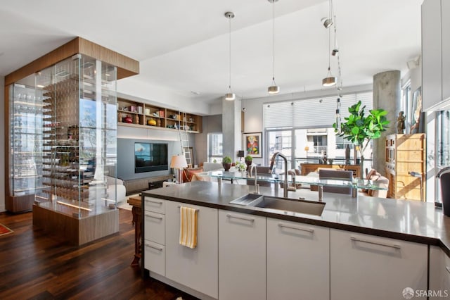 kitchen featuring dark hardwood / wood-style flooring, white cabinetry, hanging light fixtures, and sink