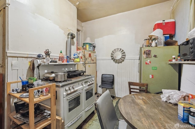 kitchen featuring range with two ovens, freestanding refrigerator, black microwave, and wainscoting