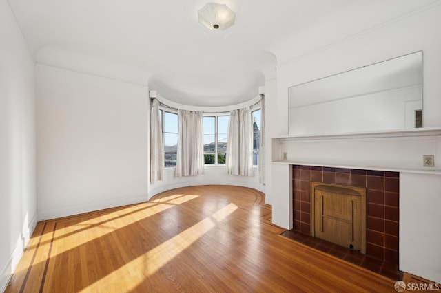 unfurnished living room featuring a fireplace, baseboards, and wood finished floors