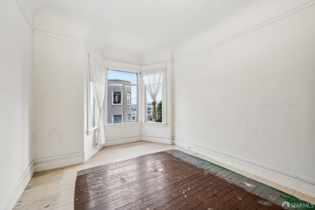 spare room with wood-type flooring and baseboards