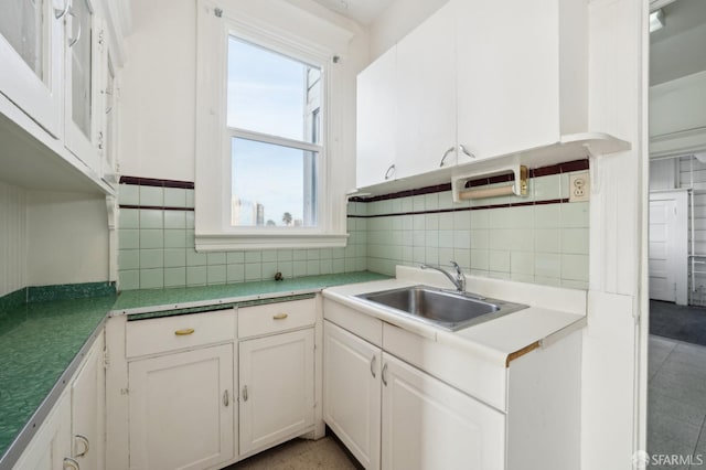 kitchen featuring light countertops, backsplash, a sink, and white cabinetry