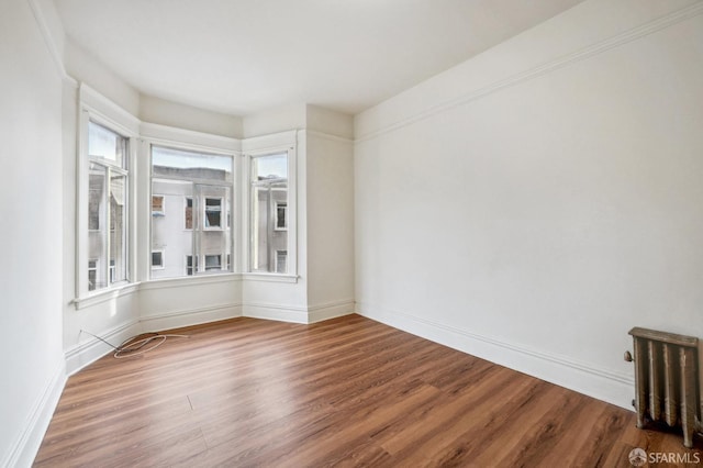 spare room with a wealth of natural light, baseboards, and wood finished floors