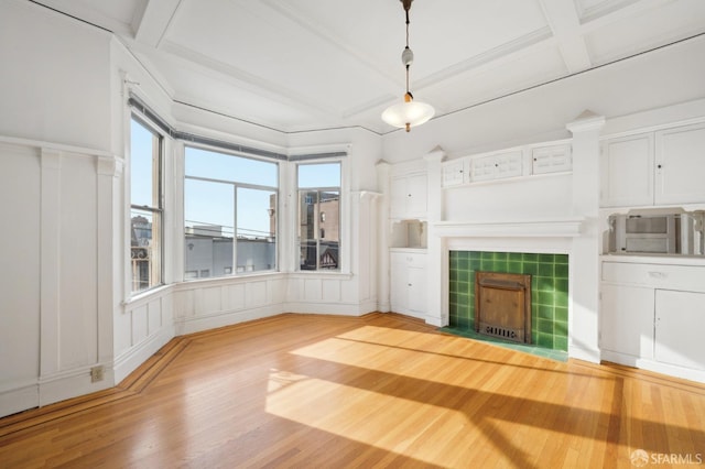 unfurnished living room with a fireplace, light wood finished floors, a decorative wall, coffered ceiling, and beamed ceiling