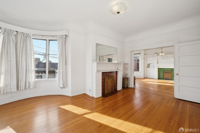 unfurnished living room featuring wood finished floors and a tile fireplace