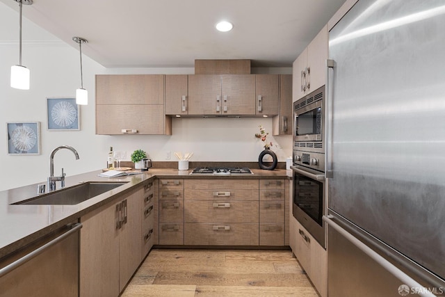 72 Townsend St Unit 302, San Francisco, CA 94107 - kitchen featuring appliances with stainless steel finishes, a sink, light wood-style floors, dark countertops, and pendant lighting