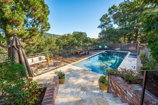 view of pool featuring an outdoor living space, a diving board, and a patio area