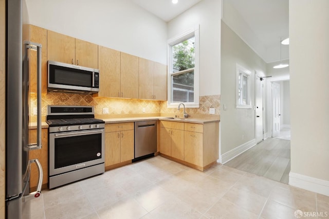 kitchen featuring light tile patterned floors, appliances with stainless steel finishes, backsplash, light brown cabinetry, and sink