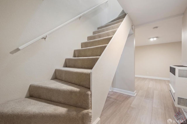 staircase featuring heating unit and hardwood / wood-style flooring