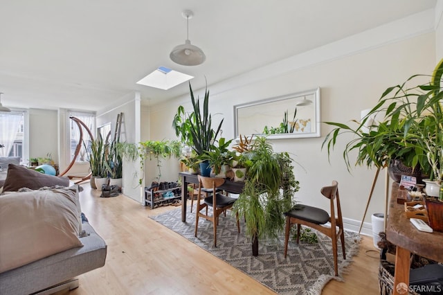 dining space featuring light wood-type flooring, a skylight, and ornamental molding