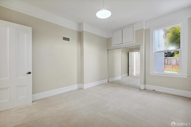 unfurnished bedroom featuring light carpet and a closet