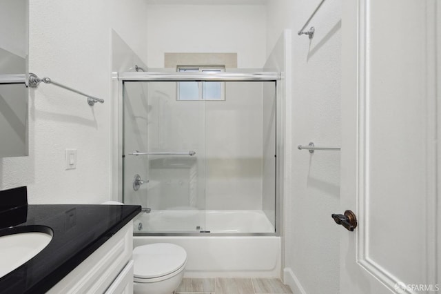 full bathroom featuring toilet, combined bath / shower with glass door, and vanity