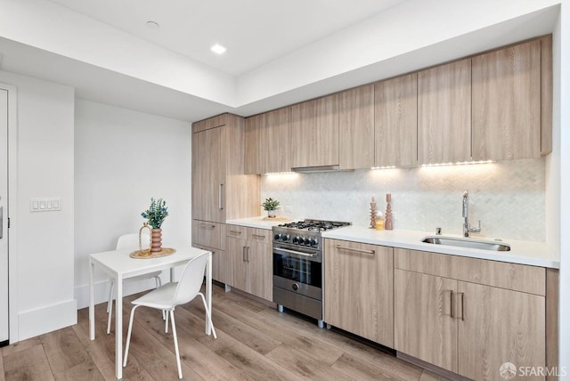 kitchen featuring sink, light hardwood / wood-style flooring, high end stainless steel range oven, and light brown cabinets