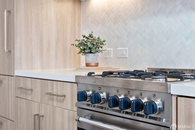 room details with tasteful backsplash, light brown cabinets, and high end stainless steel range