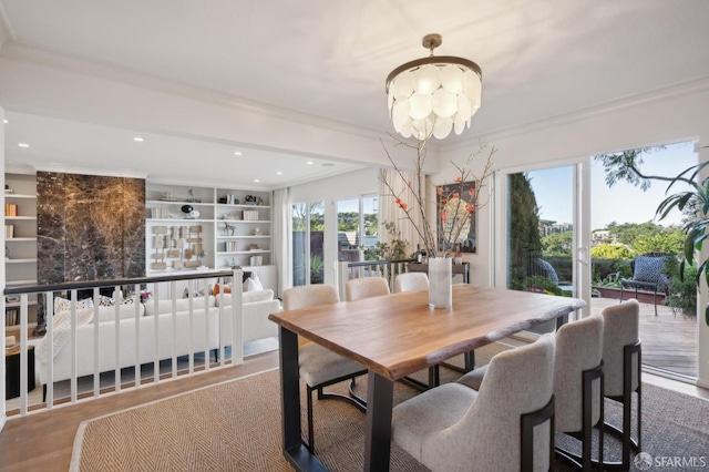 dining space with built in shelves, ornamental molding, hardwood / wood-style floors, and a notable chandelier