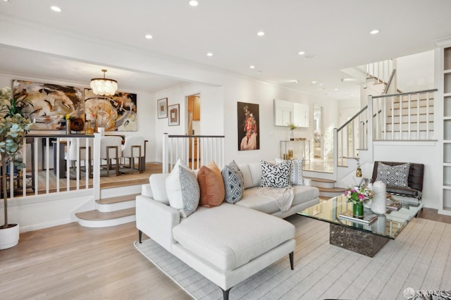 living room featuring an inviting chandelier, light hardwood / wood-style flooring, and ornamental molding