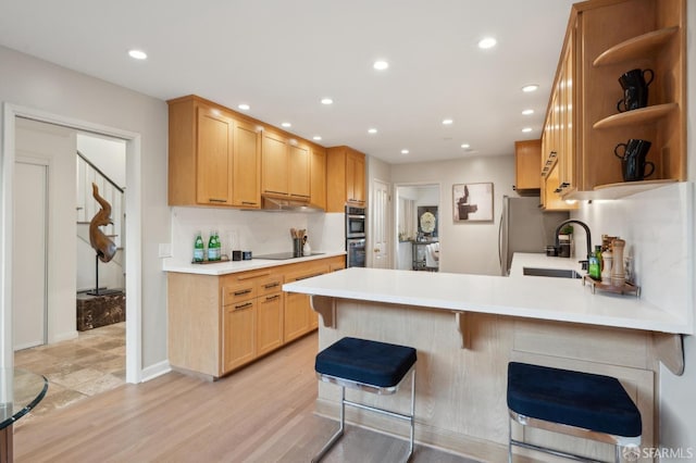 kitchen with a breakfast bar, sink, tasteful backsplash, black electric cooktop, and kitchen peninsula