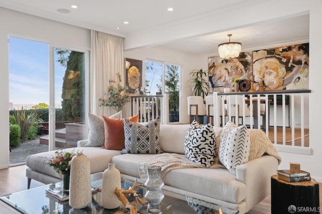 living room featuring ornamental molding, plenty of natural light, hardwood / wood-style floors, and a notable chandelier