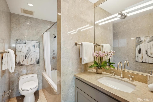 full bathroom with vanity, tile walls, toilet, and shower / bath combo