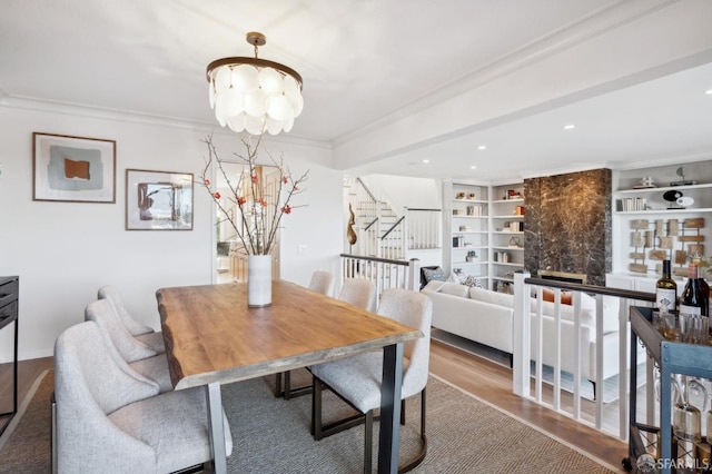 dining space with crown molding, hardwood / wood-style floors, a notable chandelier, and built in shelves