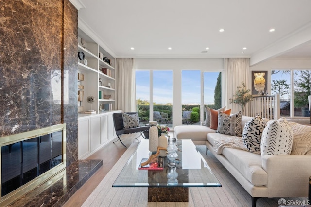 living room with crown molding, built in shelves, a wealth of natural light, and wood-type flooring