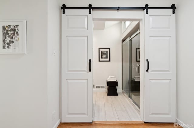 hallway with wood-type flooring and a barn door