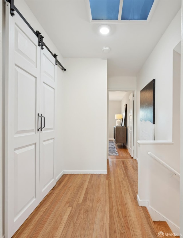 corridor with a barn door and light hardwood / wood-style floors